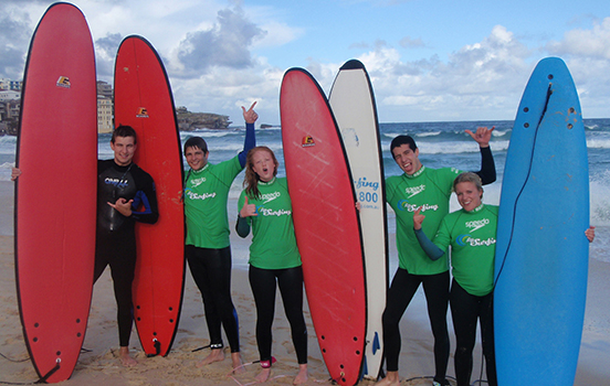 Students with surfboards on beach in Australia